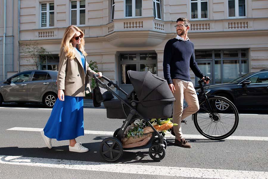 man en vrouw lopend met kinderwagen op straat