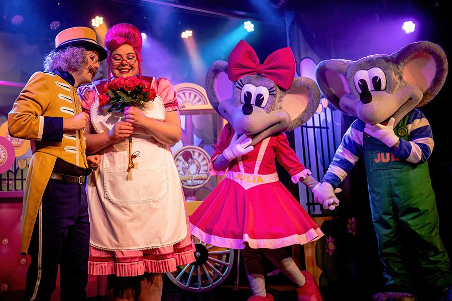 Show op het podium met twee vrolijk geklede personen en twee personen in muizenpak