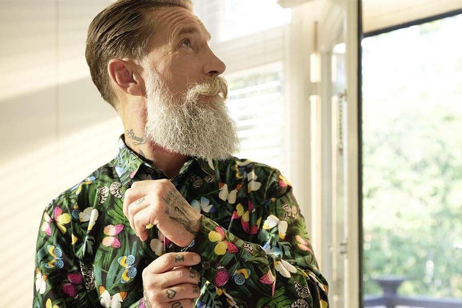een man met een baard die zijn blouse aantrekt