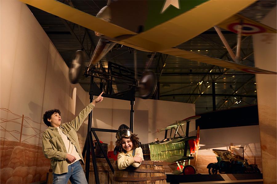 Jongen wijzend naar een oud houten vliegtuig in een vliegtuigmuseum
