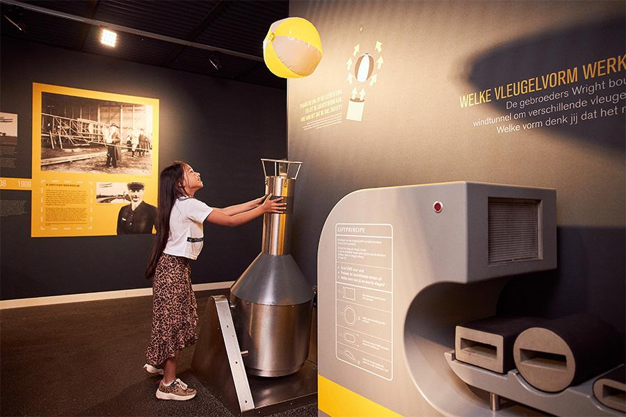 Meisje in een museum dat aan het spelen is met zwaartekracht en een strandbal