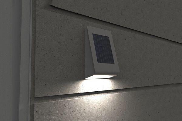 zilverkleurige brandende buitenlamp die in het donker naast een deur hangt
